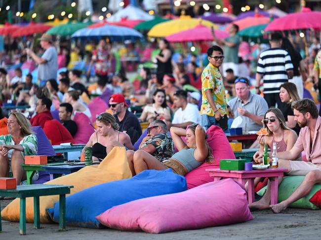 Foreign tourists relax on the Kuta Beach near Denpasar on Indonesia's resort island of Bali on November 18, 2023. (Photo by SONNY TUMBELAKA / AFP)