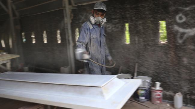 A worker at a factory outside Jakarta prepares coffins for COVID-19 victims. Picture: AP