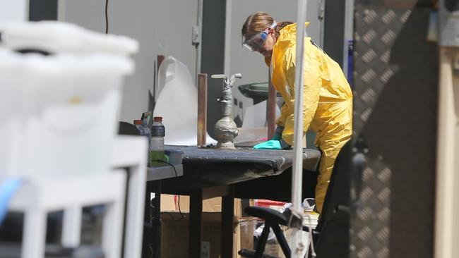 Police examine the parts of the drug manufacturing set-up. Picture: AAP / Kelly Barnes