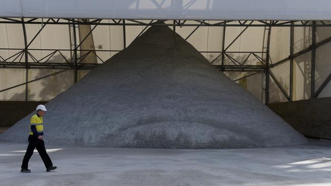 A worker walks past a pile of lithium ore whose value has rapidly collapsed. Picture: Bloomberg