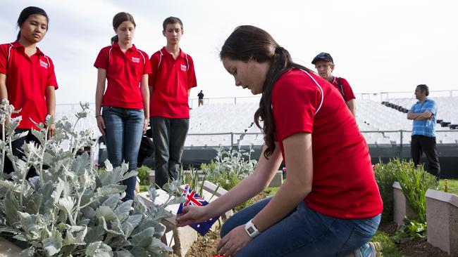 22 April 2014 - Lone Pine Cemetery, Gallipoli, Turkey. Tiffanie Turnbull from Dakabin, Queensland, winner of the Premier's Anzac Prize pays tribute to Australian soldiers at Lone Pine cemetery. In background (L-R) Pyusan Min from Townsville, Elizabeth Gardner from Brisbane, Mackenzie Plath from Gladstone. Pic Ella Pellegrini