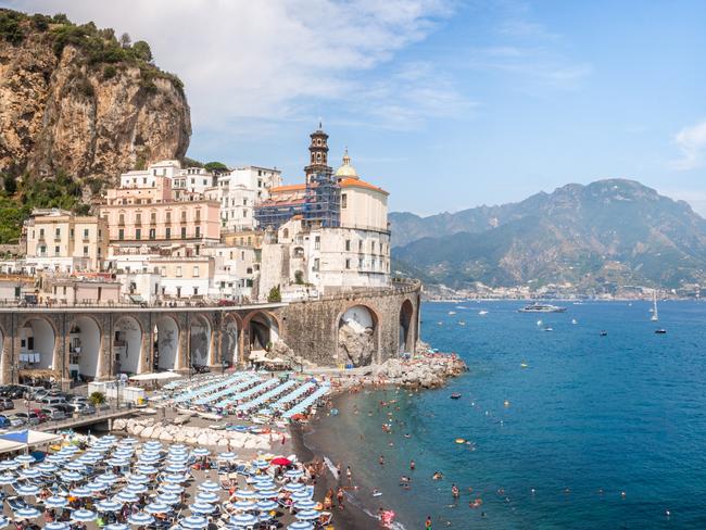 EMBARGO FOR TWAM, 30 NOVEMBER 2024. FEE MAY APPLY. Picture shows the village of Atrani as seen from an elevated viewpoint, with a view on its crowded white sand beach with umbrellas, its old fortifications, the dome and bell tower of the local church (Santa Maria Maddalena, XIIIth century) and its traditional houses with colorful facades covered with lime. In the background, other parts of the Amalfi Coast can be seen: the villages of Maiori and Minori and the mountains above them. Atrani is one of the most famous village and the image of the Amalfi Coast. It is classified as an UNESCO World Heritage Site since 1997, as part of the inscription of the whole Amalfi Coast, and is also labelled I Borghi piÃÂ¹ belli d'Italia ("The most beautiful villages of Italy").