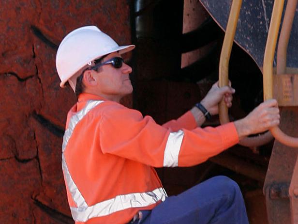 A worker climbs a ladder to enter the cab of a large ore moving truck at the Telfer Mine in the Pilbara region of Western Australia, Thursday, July 28, 2005. Newcrest Mining Ltd., the biggest Australian gold miner, has yet to decide whether to invest in the development of the A$1 billion ($755 billion) Boddington gold mine in Western Australia. Photographer: Will Burgess/Bloomberg News.