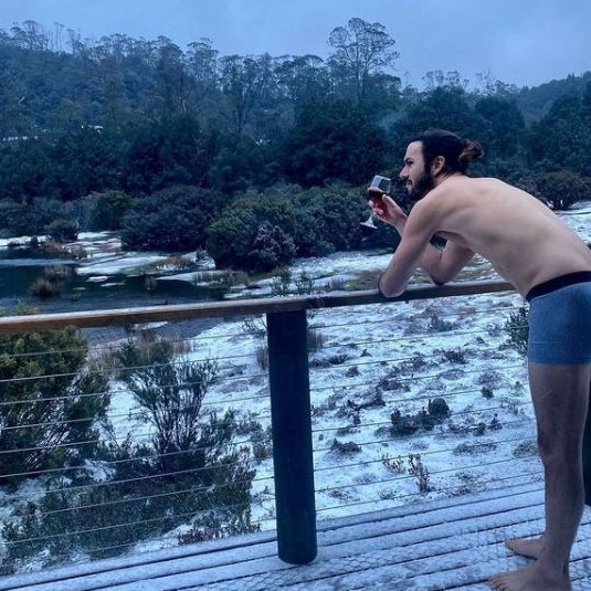 Perth tourist Paul Erlynne enjoys a glass of Pinot in the snow at Cradle Mountain. Source: Supplied.