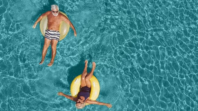 High angle view photo of a senior couple floating in the ocean while using swimming and floating devices; Retirement, travel generic retirees