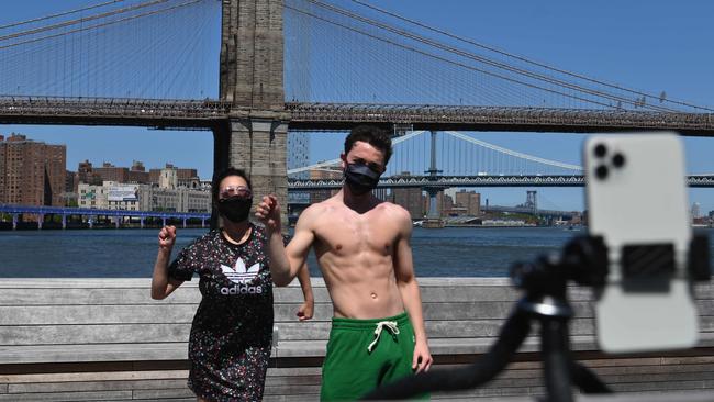 Actor Marie Zaccagnino and musician Sean Sheridan dance and record themselves for a TikTok video in front of the Brooklyn Bridge in New York City. Picture: Angela Weiss/AFP