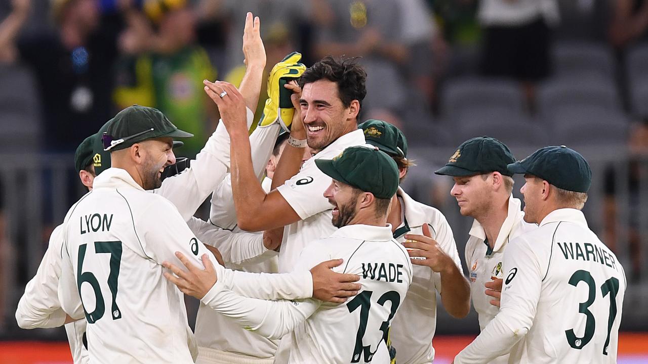 Mitchell Starc is mobbed by teammates after snaring a wicket late on day two in Perth.