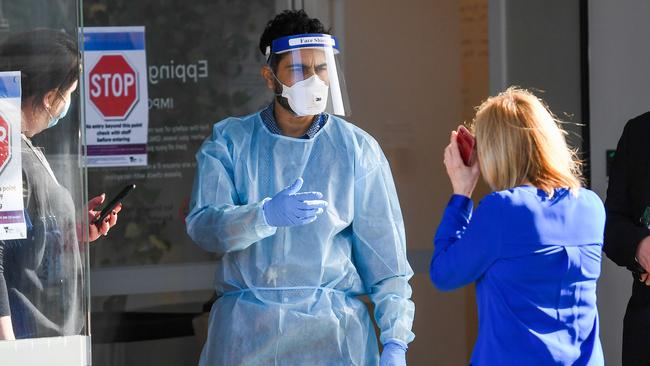 A relative speaks to medical workers at the entrance of the Epping Gardens aged care facility