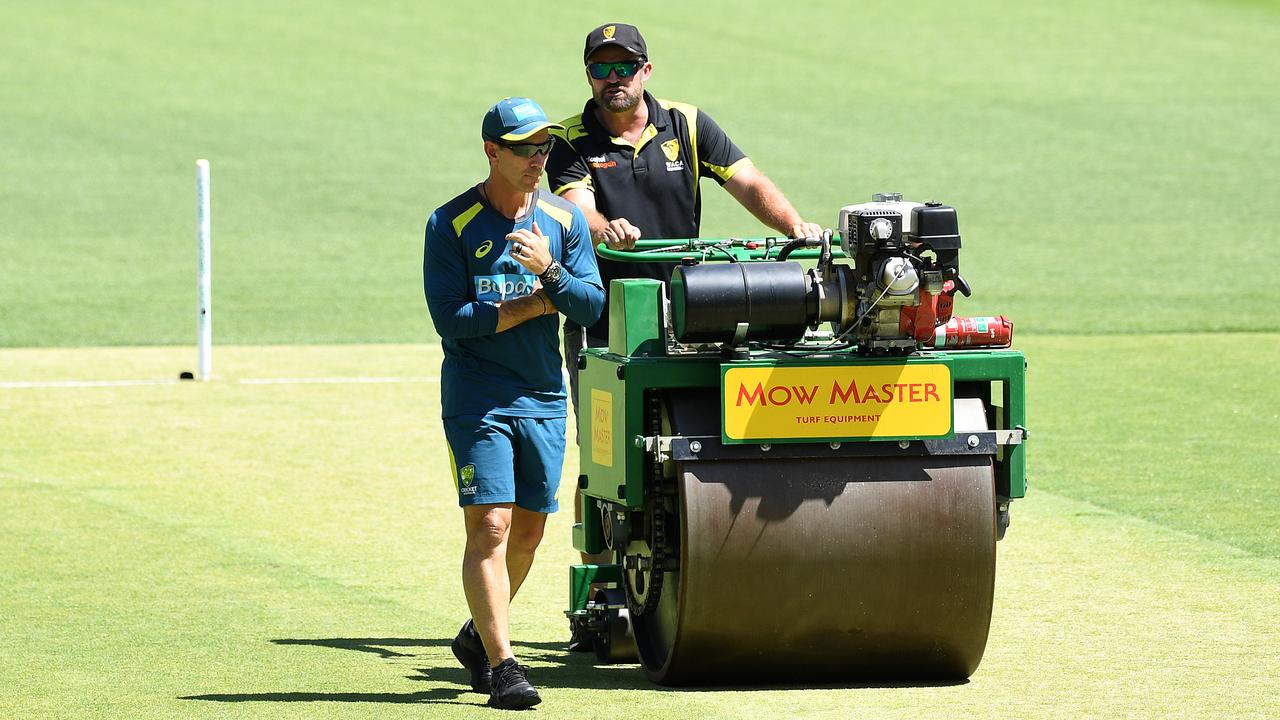 Australian coach Justin Langer (left) inspects the pitch as curator Brett Sipthorpe rolls the wicket.