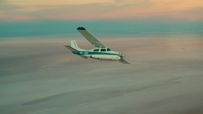 Charles Wooley flies over Lake Eyre with the shifting colours of the transcendent sky and landscape surrounding the lake making a stunning backdrop. Picture: Arron Hage