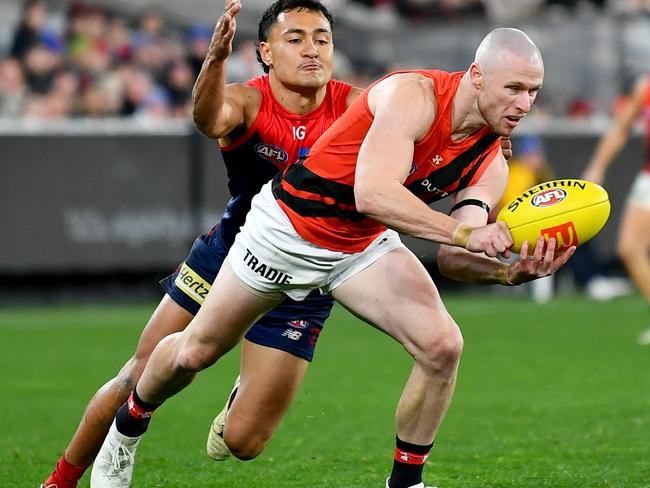 MELBOURNE, AUSTRALIA - JULY 13: Nick Hind of the Bombers handballs whilst being tackled by Andy Moniz-Wakefield of the Demons during the round 18 AFL match between Melbourne Demons and Essendon Bombers at Melbourne Cricket Ground, on July 13, 2024, in Melbourne, Australia. (Photo by Josh Chadwick/AFL Photos/via Getty Images)