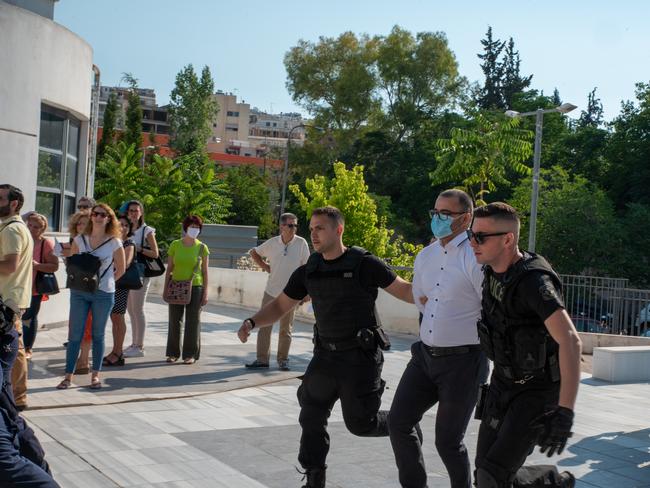 Milen Raychev, the brother of Yuliyanov J Raychev Serafim, who is accused of being an accessory to the murder of John Macris, is lead into court in Athens by police. Picture: Spyros Bakalis