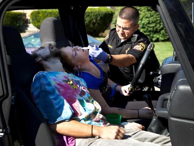 A police officer administers Narcan to try and counteract the opioids in their bodies. Picture: Dan Callister