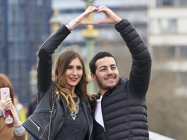 TOPSHOT - People pose for photographs on Westminster Bridge in central London on March 23, 2017 after the bridge reopened to traffic following its closure during the March 22 terror attack. Britain's parliament reopened on Thursday with a minute's silence in a gesture of defiance a day after an attacker sowed terror in the heart of Westminster, killing three people before being shot dead. Sombre-looking lawmakers in a packed House of Commons chamber bowed their heads and police officers also marked the silence standing outside the headquarters of London's Metropolitan Police nearby. / AFP PHOTO / NIKLAS HALLE'N