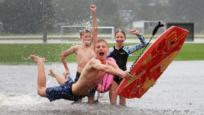 Siblings Ziggy Martin (13) and Poppy Martin (10) watch big brother Kieren Lee (15) make the most of flood water which swamped their soccer field at Coplicks Sports Park on Tallebudgera Connection Road, Tallebudgera , after torrential rain over night caused the creek to break its banks. NCA NewsWire / Scott Powick