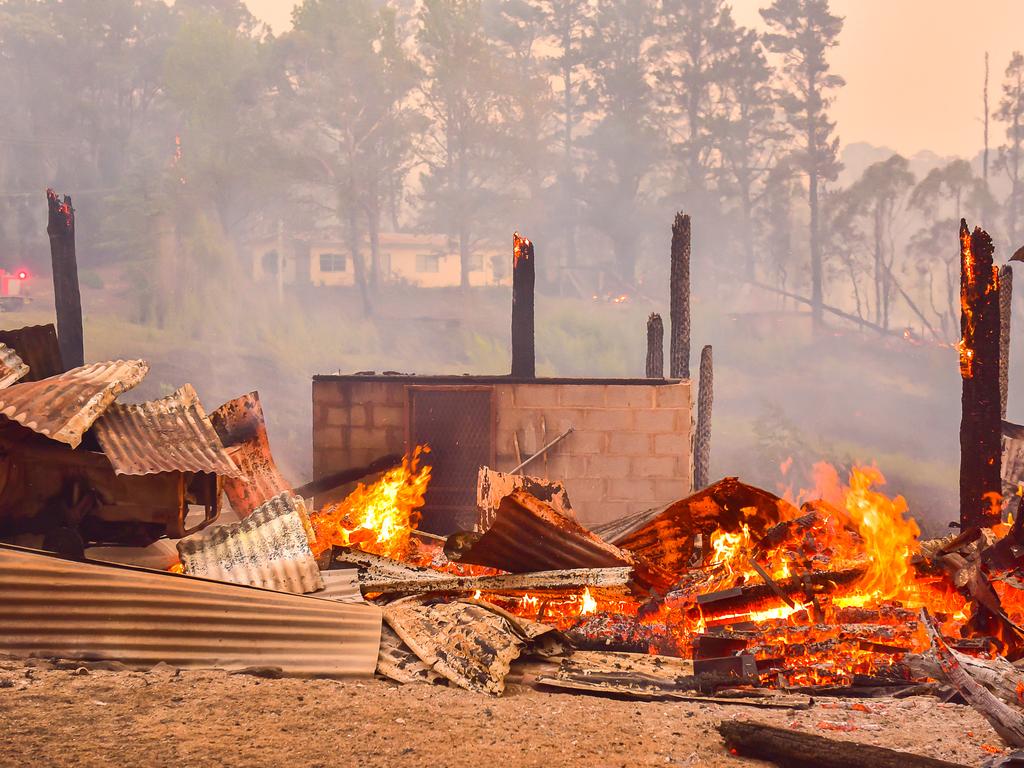 An out of control fire ripped through the Blue Mountains this afternoon. Unknown houses and other property has been destroyed along Bells Line of Road from Bilpin to Mount Tomah and further west. The remains of a house along Bells Line of Rd at Bilpin. Firefighters battle to protect property in the background. Picture: Matrix