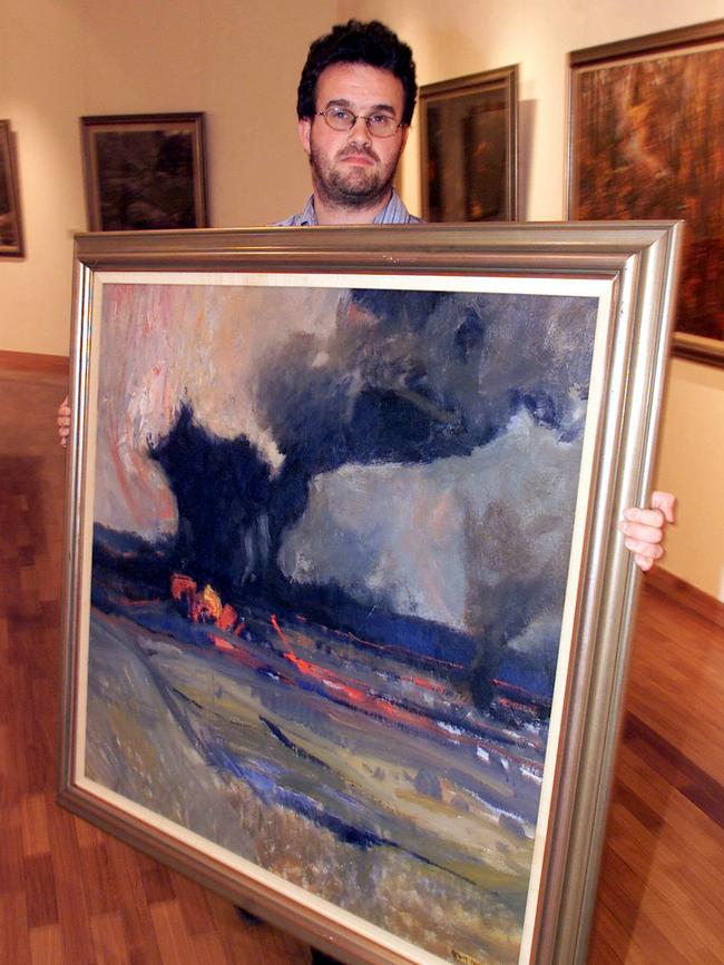 Gosford Regional Gallery curator Tim Braham with a painting by Carroll recording a bushfire near his Bathurst home.