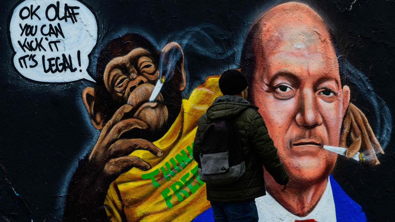 A man walks past a mural by Berlin-based graffiti artist Eme Freethinker depicting a chimpanzee handing a joint to a likeness of German Chancellor Olaf Scholz. Picture: John MACDOUGALL / AFP