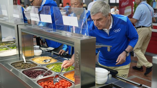 PARIS, FRANCE - JULY 22: IOC President Thomas Bach tries food from a salad bar while touring the Olympic Village ahead of the start of the Paris 2024 Olympic Games on July 22, 2024 in Paris, France. (Photo by David Goldman - Pool/Getty Images)