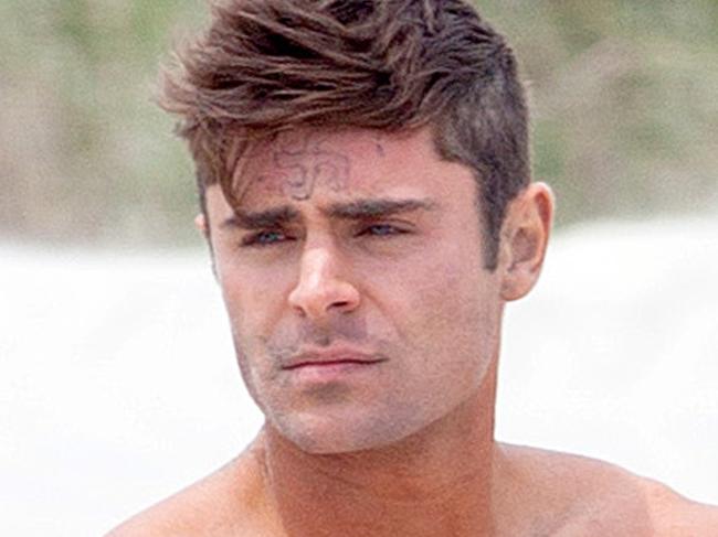 UK CLIENTS MUST CREDIT: AKM-GSI ONLY Zac Efron took a short break from filming 'Dirty Grandpa' on Tuesday afternoon on Tybee Island, GA, goofing off on the beach and snapping photos with a young boy. The 27-year-old stud remained shirtless with the words 
