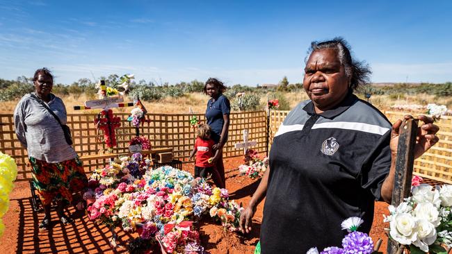 Kumanjayi Walker's foster mother Leanne Oldfield (right) visiting his grave in Yuendumu with two of Walker's other relatives, Meggerie Brown and Lara.