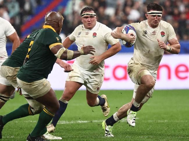 England's openside flanker Tom Curry (R) runs with the ball during the France 2023 Rugby World Cup semi-final match between England and South Africa at the Stade de France in Saint-Denis, on the outskirts of Paris, on October 21, 2023. (Photo by Anne-Christine POUJOULAT / AFP)