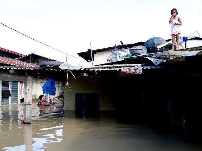 A couple wade through floodwaters to buy drinking water in the Philippines. Picture: AP