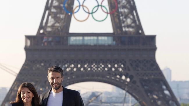 Paris mayor Anne Hidalgo and French President of the Paris 2024 Olympics and Paralympics Organising Committee (Cojo) Tony Estanguet pose in front of the Eiffel Tower after the installation of the Olympic rings on the tower for the upcoming Paris 2024 Olympic Games, in Paris on June 7, 2024. (Photo by JOEL SAGET / AFP)