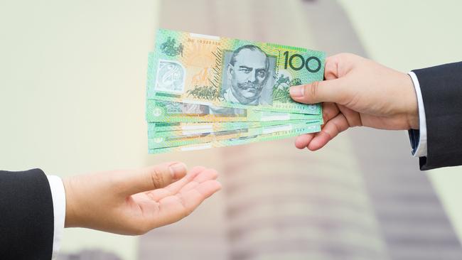 Hands of businessman passing Australian dollar (AUD) banknote with blurred office building background. . Picture: iStock