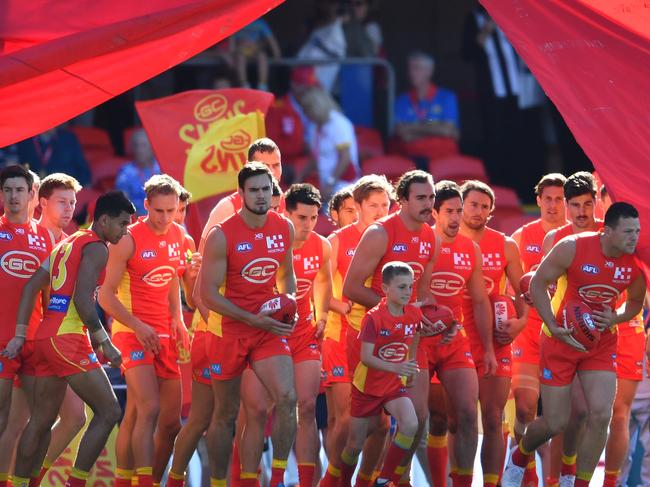 Suns players run through the banner before the Round 21 AFL match between the Gold Coast Suns and the Richmond Tigers at Metricon Stadium. Picture: AAP Image/Darren England.