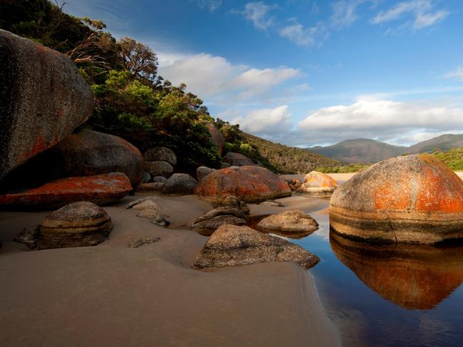 Pre-historic rocky outcrops covered in orange lichen at Tidal River.Wilsons Promontory National Park › Ancient rocks, highlighted in orange lichen, litter the bays and inlets of Tidal River on the west side of Wilsons Promontory National Park. Squeaky Beach is a popular one-hour hike from Tidal River. Or pack a tent to reach Refuge Cove or Sealers Cove for the night.FROM BEAUTIFUL WORLD AUSTRALIA (LONELY PLANET)Picture: Pete Seaward