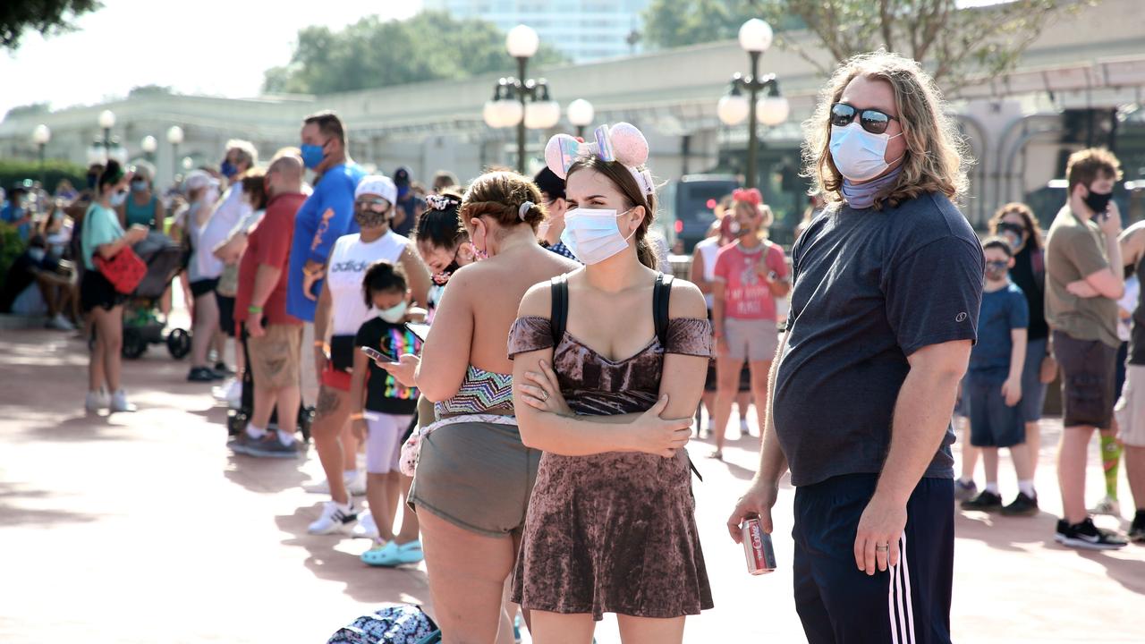 Guests wearing protective masks wait outside the Magic Kingdom theme park at Walt Disney World on the first day of reopening, in Orlando, Florida. (Photo by Gregg Newton / Gregg Newton / AFP)