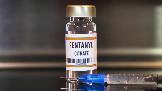 Fentanyl drug and syringe on black table with reflections and stainless background.