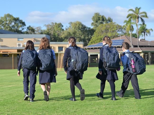 Group of Australian school students wearing school uniform walking together to school in the morning time.