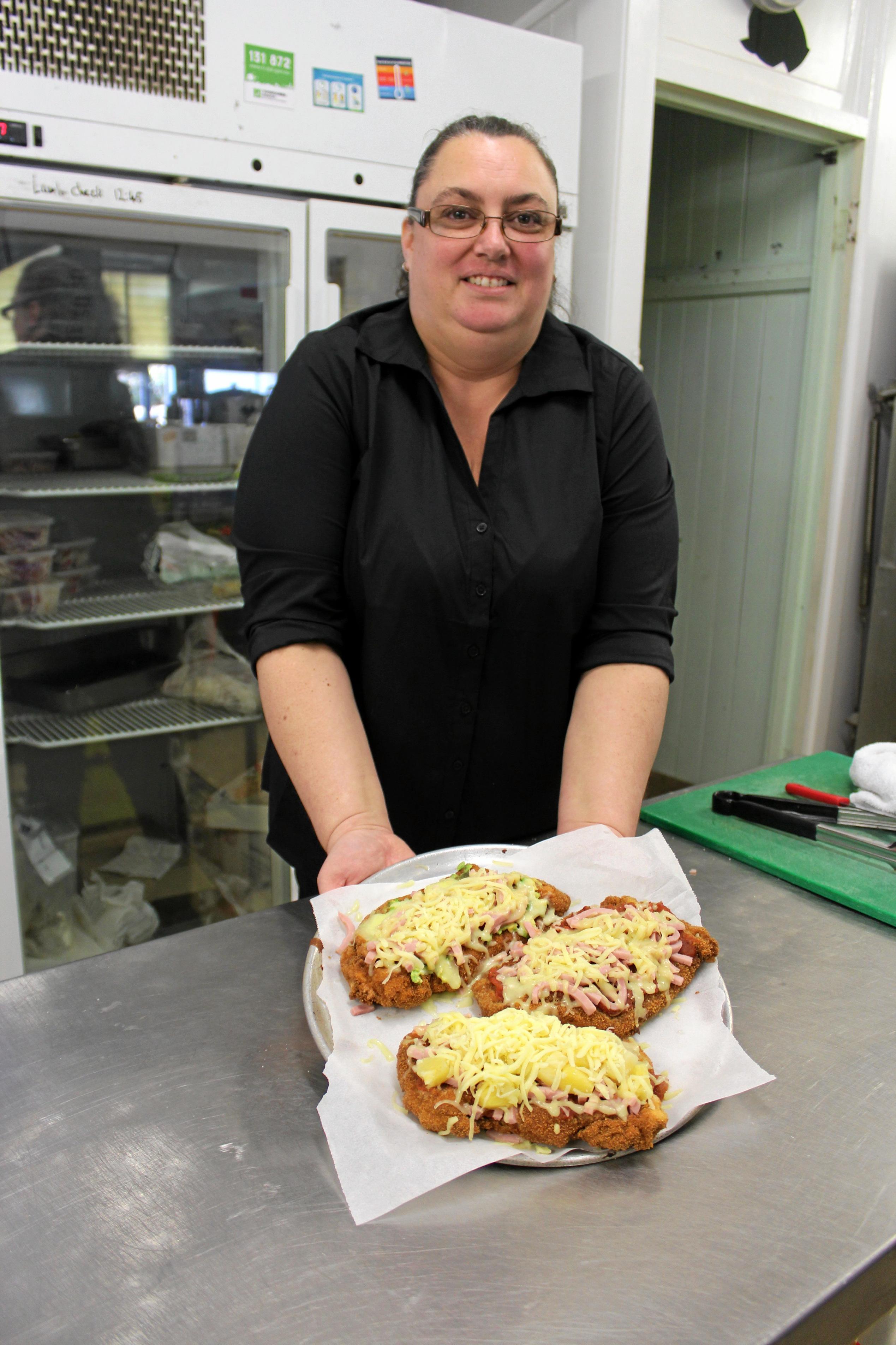 Head Cook Stacey Ellwood holding up the Hawaiian, Golden Buick and Traditional Chicken Parmies before putting them in the oven to cook. Picture: Laura Blackmore