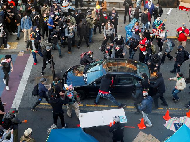 A man tries to enter the vehicle of a man who tried to drive through the crowd during a protest. Picture: Reuters