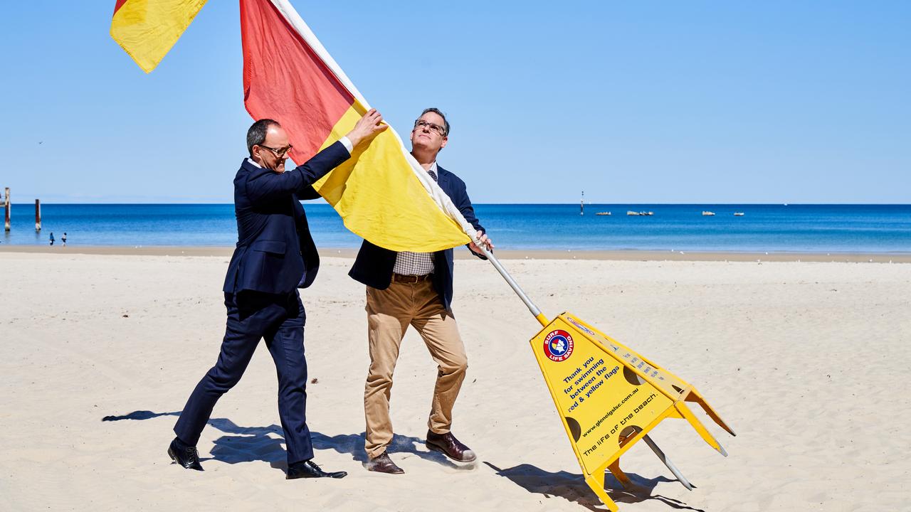 Emergency Services Minister Corey Wingard and Surf Life Saving SA President John Baker raise the flags in Glenelg to signal the start of the Surf Life Saving season. Picture: Matt Loxton