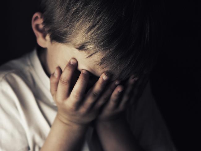 Depressed 6 years old child crying. Dark background.