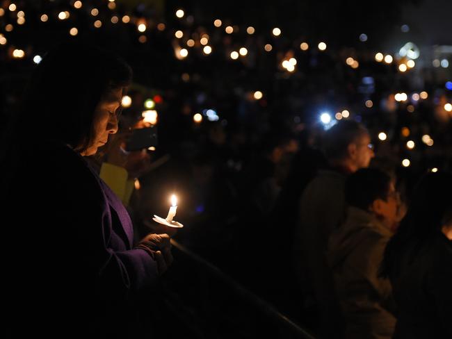 Remembrance ... People hold candles during a vigil for shooting victims on Thursday at San Manuel Stadium in San Bernardino, California. Picture: Mark J. Terrill.