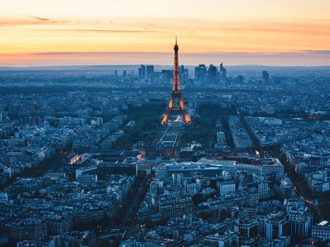 SUNDAY ESCAPE. DOC HOLIDAY. Paris, France - May 1, 2016: View from Montparnasse tower on Paris cityscape with Eiffel Tower at sunset. Illuminated Eiffel tower is located in the middle of Champ-de-Mars. A business district La Defence is in the background. Picture: iStock