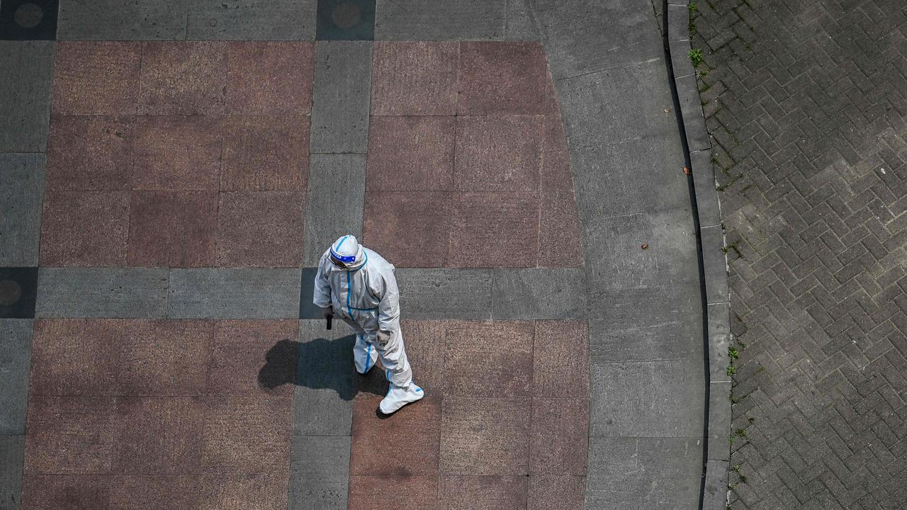 A worker wearing personal protective equipment waits while residents undergo a health screening in Shanghai on April 19, 2022. Picture: Hector Retamal / AFP