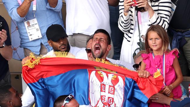 Novak Djokovic celebrates victory in his box with the Serbian flag. Picture: Getty Images