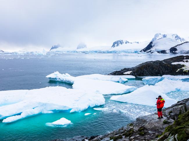 Tourist taking photos of amazing frozen landscape in Antarctica with icebergs, snow, mountains and glaciers, beautiful nature in Antarctic Peninsula with icecredit: iStockescape19 august 2021doc holiday