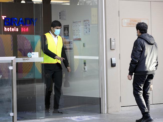 A staff member lets a man in the front door of the Brady Hotel in Melbourne CBD. The hotel has been given the contract to act as a Covid 19 quarantine centre. Picture: NCA NewsWire / David Geraghty