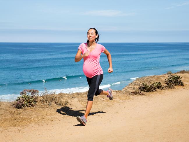 A beautiful pregnant woman running on the nature trail overlooking the ocean in San Diego, California.  She is in her third trimester (7 months) and wearing a pink maternity sports top and leggings. She's been a runner and continues to jog regularly to stay fit and strong during pregnancy. Being physically active is important for a healthy pregnancy.istock