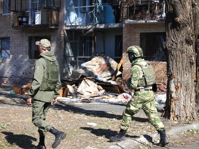 Local volunteers walk past a building damaged by Ukrainian strikes in Kursk on August 16, 2024, following Ukraine's offensive into Russia's western Kursk region. Two people were killed while evacuating civilians from Russia's western Kursk region, where Ukraine is staging a major cross-border offensive, a pro-Kremlin organisation said August 16. Russia has evacuated more than 120,000 from towns and villages near the border with Ukraine since Kyiv launched its surprise border incursion last week. (Photo by TATYANA MAKEYEVA / AFP)