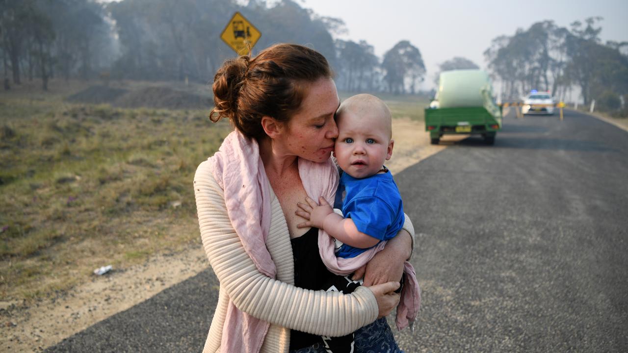 Wytaliba resident Storm Sparks holds her son Zeke as she waits to get back to her house at a roadblock near Glen Innes on Monday. Picture: AAP