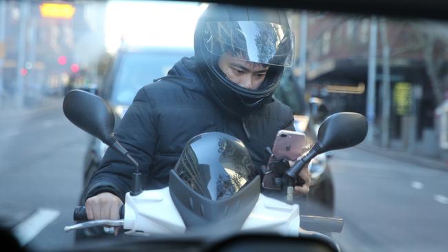 A motorbike rider uses a mobile phone while driving. Picture; John Grainger