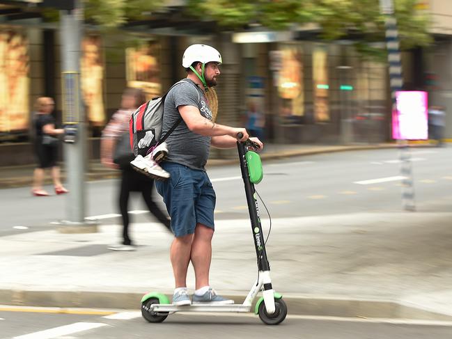 A Lime user crosses the street in Brisbane’s CBD in Brisbane. Picture: AAP/Albert Perez