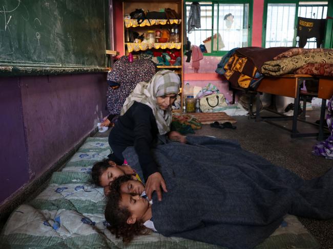 A Palestinian woman covers her sleeping children with a blanket as they take refuge in a United Nations school in the Rafah refugee camp. Picture: Mohammed Abed/AFP